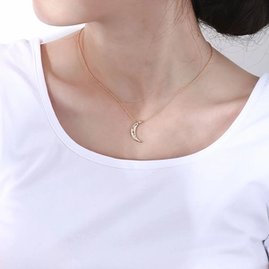 Macro shot of gold moon necklace pendant featuring sparkling pave set zircons on neck