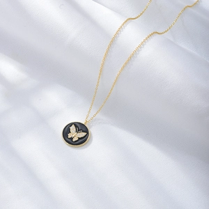Detail of a gold butterfly pendant with sparkling diamonds and black enamel texture