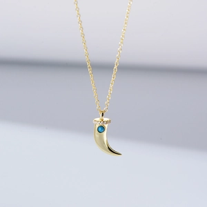 Detailed view of crescent pendant with turquoise stone and zircon accents on gold chain