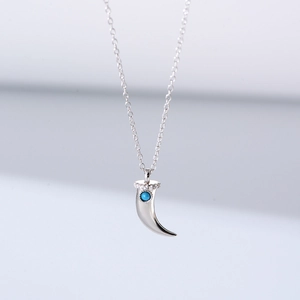 Macro view of sterling silver horn pendant with turquoise stone and zircon inlay details