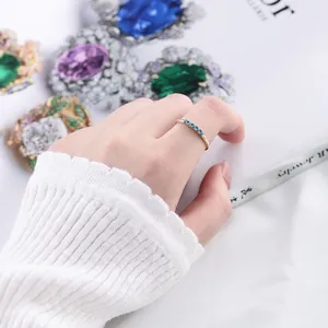 Détail d'une fine bague en argent 925 doré avec cinq petites pierres turquoise au doigt