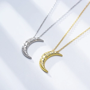 Close-up of crescent moon necklaces in silver and gold with star-set cubic zirconia detail