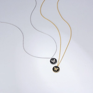 Close-up of gold and silver butterfly necklaces with black enamel and zircons