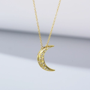 Macro detail of crescent moon pendant with white zircons and gold star engraving