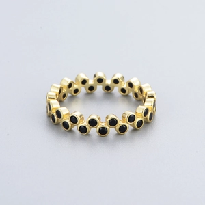 Macro detail of gold eternity ring featuring alternating black zircon stones set in a wave pattern