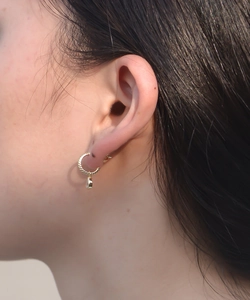 Close-up of golden twist hoop earrings with clear teardrop zircon pendants on ear