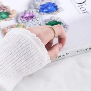 Close-up of a delicate gold eternity ring with round zircons worn by a model