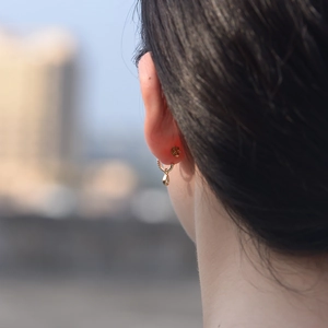 Close-up of golden teardrop pendant earrings worn by a model in soft outdoor light