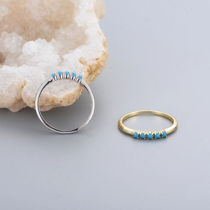 Macro detail of 925 silver and gold rings featuring five turquoise stones on a crystal