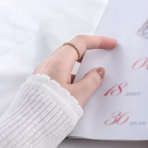 Close-up of a gold hexagonal band ring with pavé-set small diamonds on a model's finger