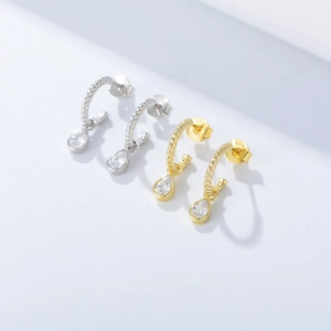 Detail of twisted S925 silver hoop earrings with teardrop zirconia in gold and silver