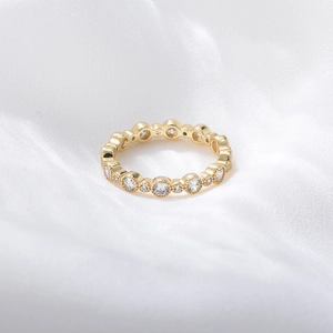 Detailed close-up of gold geometric eternity ring with micro-pave zircons and beaded edges