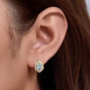 Geometric silver stud earrings with blue topaz and diamonds on a female model