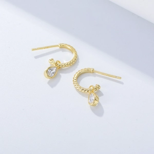 Detailed shot of golden twisted C-shape earrings featuring clear teardrop zircon drops