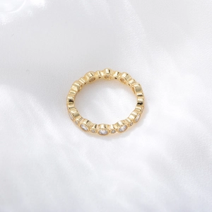 Macro shot of gold eternity ring with bezel set round cubic zirconia on white silk