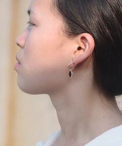 Détail de boucles d'oreilles vintage dorées avec pendentif en agate noire sur modèle