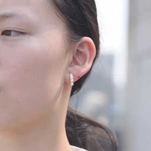 Detail of four white pearls vertically arranged on a gold sterling silver stud earring