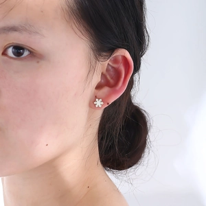 Macro view of a snowflake stud earring with pavé zircon settings worn on the ear