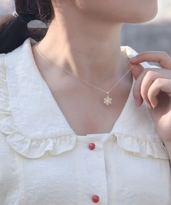 Close-up of golden snowflake pendant with zircons worn by model on elegant white top