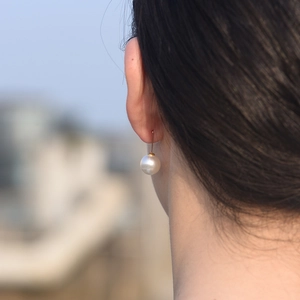 Gros plan de boucles d'oreilles minimalistes en argent S925 et perles portées par un modèle
