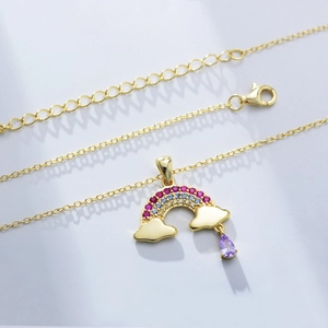 Macro detail of gold rainbow pendant necklace with colorful stones and purple teardrop gem