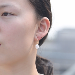 Boucles d'oreilles perles d'eau douce baroques avec crochets dorés portées par un modèle