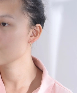 Detail of minimalist gold hoop earring with sparkling round zircon drop on model
