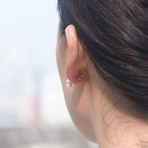 Detail of cluster pearl stud earrings in gold finish worn by a model in natural light