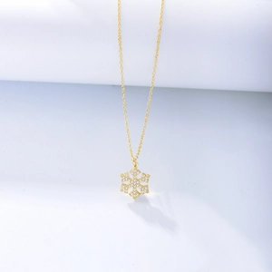 Macro shot of gold-plated snowflake pendant with shimmering crystals on a fine chain