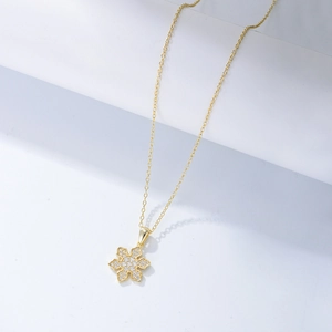 Detailed view of a gold snowflake pendant featuring micro-set sparkling cubic zirconia