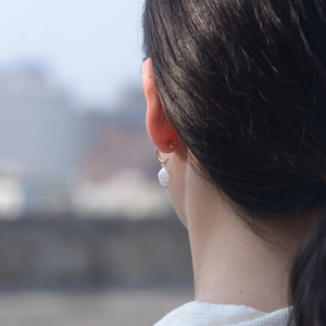 Vue détaillée de boucles d'oreilles en perles baroques portées avec crochets dorés