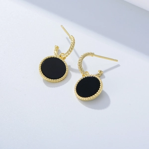 Détail macro de boucles d'oreilles onyx noir rétro avec texture corde dorée torsadée