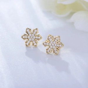 Detailed close-up of golden snowflake stud earrings with sparkling pavé zircon stones