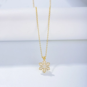 Detailed close-up of a gold snowflake pendant necklace featuring sparkling zircon stones