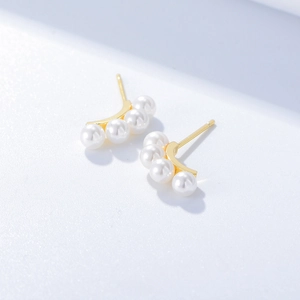 Detailed view of four white pearls arranged in an arc on a gold stud earring base