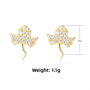 Detailed macro view of gold-plated leaf stud earrings with sparkling cubic zirconia stones