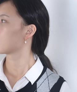 Gros plan d'un mannequin portant une créole dorée avec pendentif fraise en émail blanc