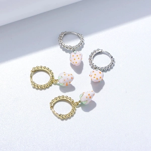 Gros plan de boucles d'oreilles fraise en émail argent 925 avec finitions or et argent