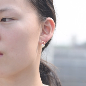 Minimalist gold C-shaped 925 sterling silver earrings with a white pearl on a female model