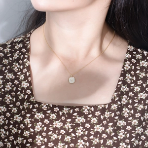 Close-up of a gold s925 silver necklace featuring a round pendant with a heart crystal