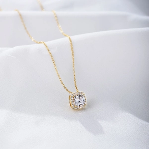 Macro shot of gold square zircon pendant on white satin fabric for a minimalist necklace