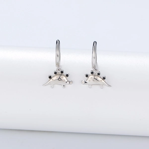 Close-up of S925 silver stegosaurus earrings with black stone accents and etched details