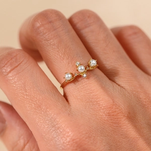 Anello ramo placcato oro con perle bianche e cristalli scintillanti sulla mano