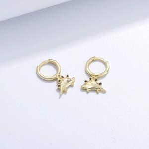 Close-up of gold stegosaurus earrings with black gemstone accents on white surface