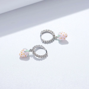Détails macro de boucles d'oreilles fraise en argent S925 avec émail rose et feuilles vertes