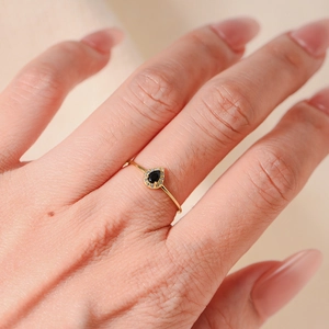 Macro detail of gold teardrop ring with black pear-cut stone and micro-pave crystals