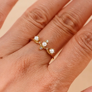 Primo piano di un anello corona dorato con tre perle e zirconi lucenti dal design elegante