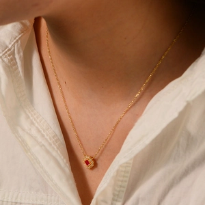 Dettaglio di una collana d'oro con ciondolo in rubino quadrato e alone di zirconi