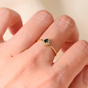 Minimalist gold ring with pear-cut black zircon and micro-paved diamonds on finger