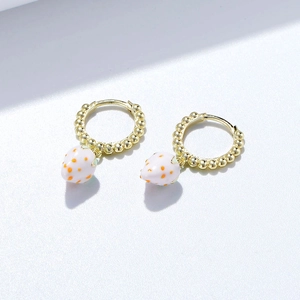 Vue macro de boucles d'oreilles fraise en argent s925 avec créoles dorées et émail blanc